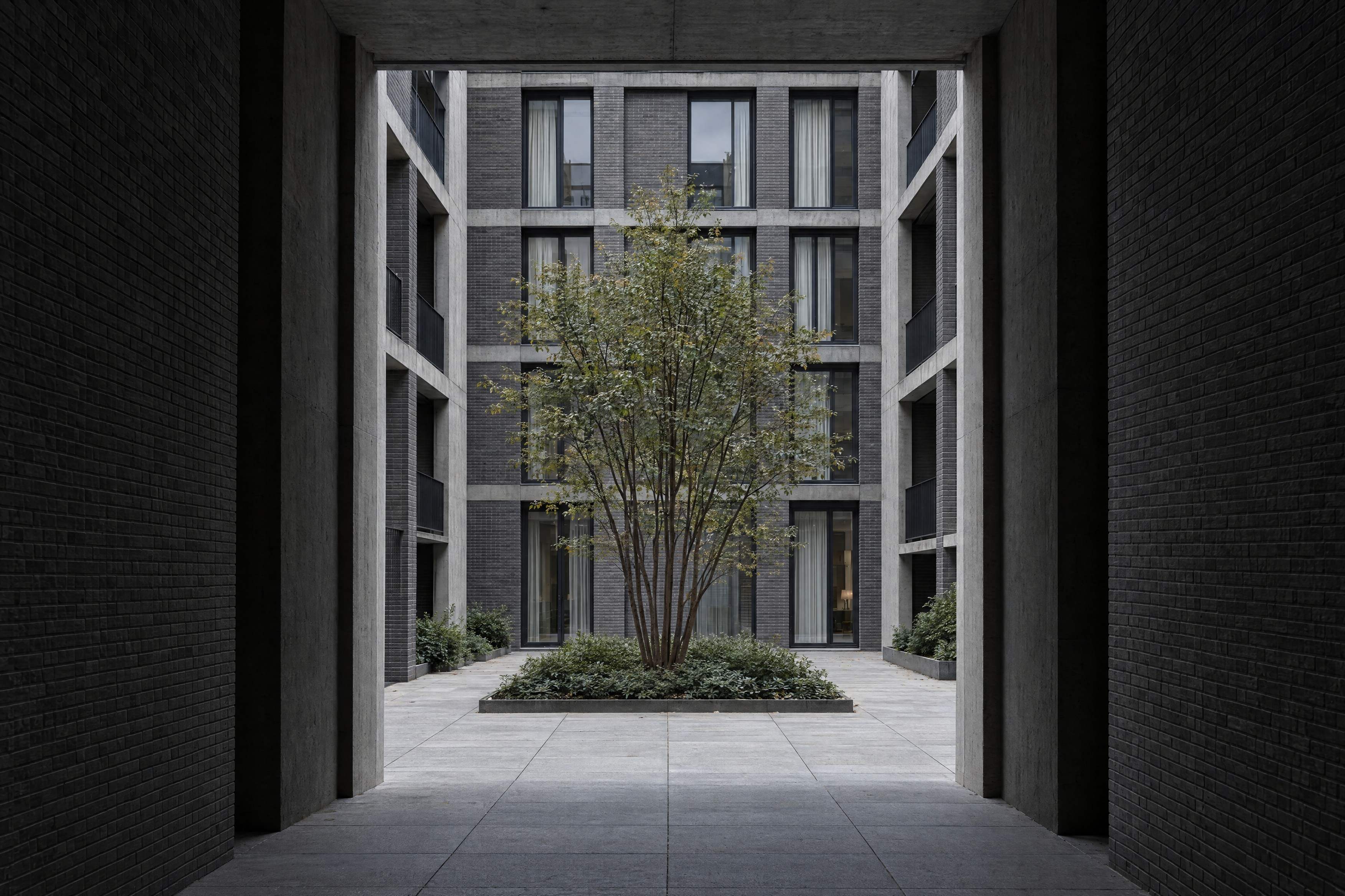 View through a passage into a quiet courtyard with a tree