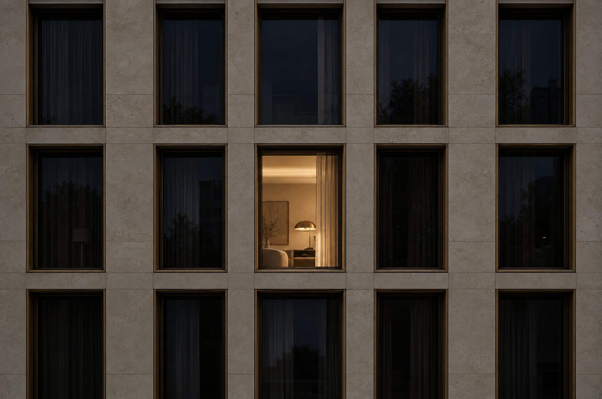 Natursteinfassade mit einem beleuchteten Fenster bei Nacht