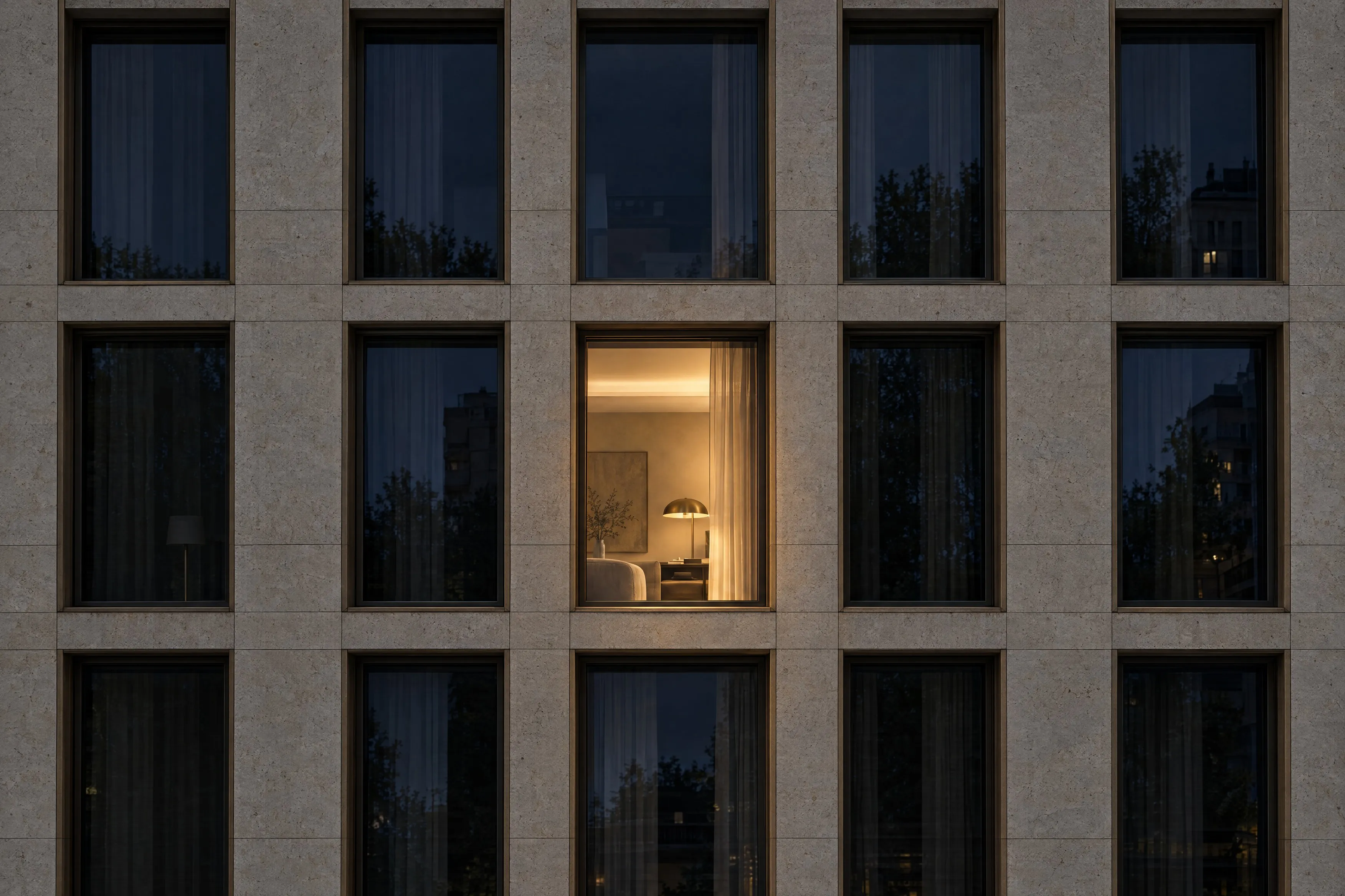 Natursteinfassade mit einem beleuchteten Fenster bei Nacht