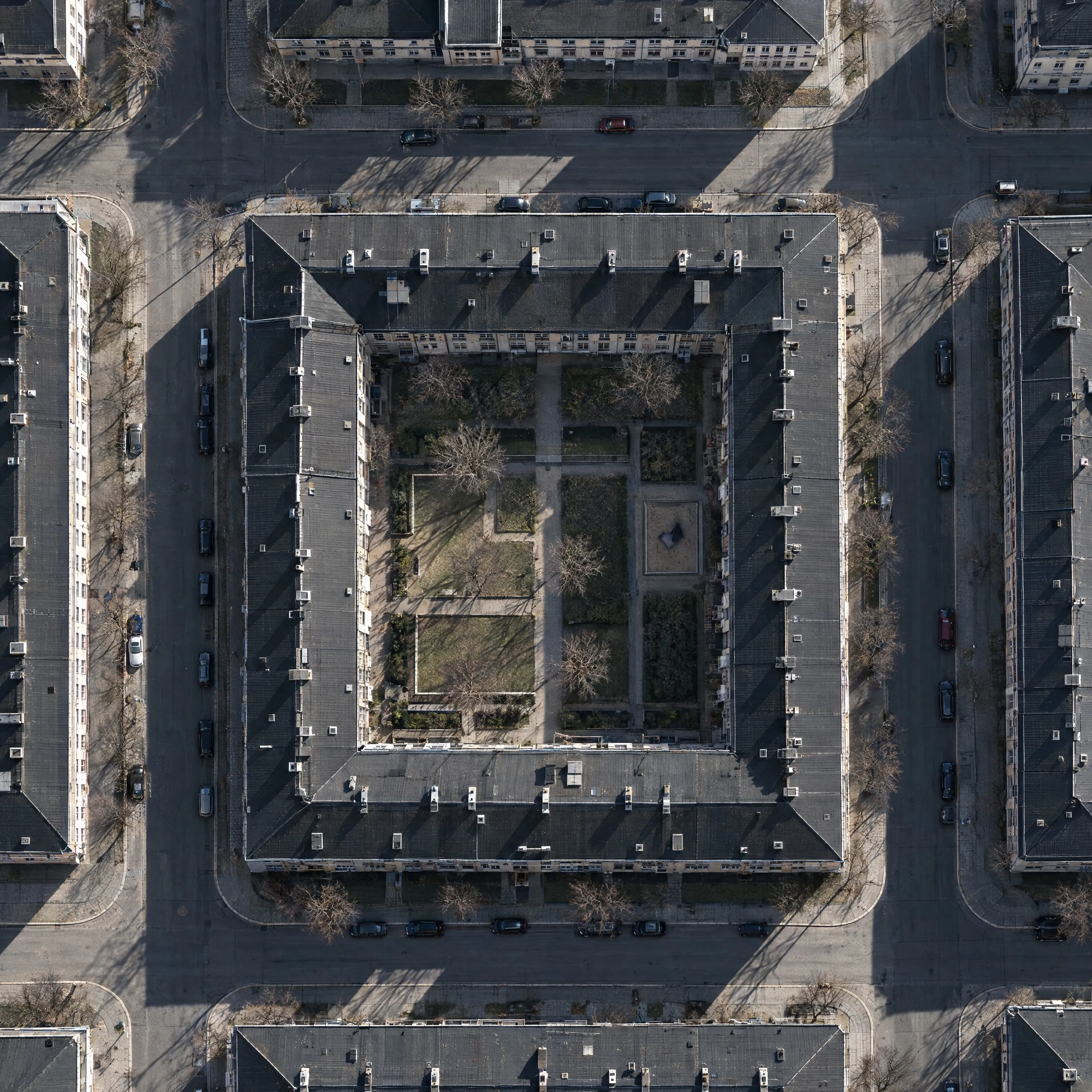 Luftaufnahme eines Wohnblocks mit Innenhof und langen Schatten