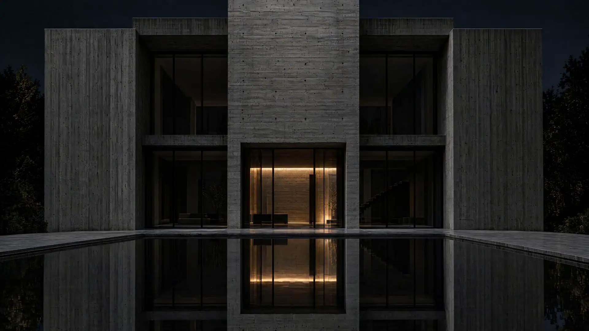Monolithisches Gebäude aus Sichtbeton bei Nacht, ein Lichtband im Eingang spiegelt sich im Wasserbecken